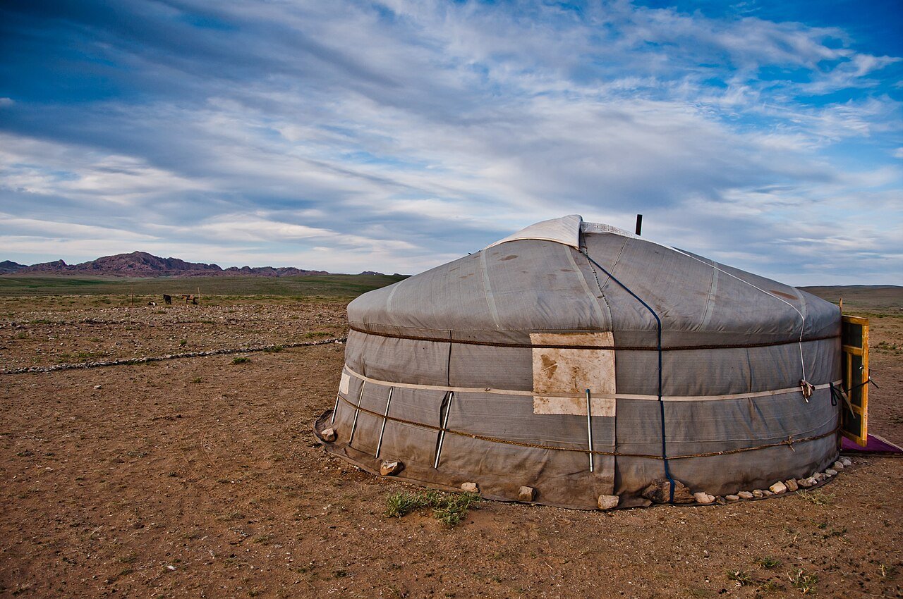 A traditional ger on the open Mongolian steppe under a dramatic sky