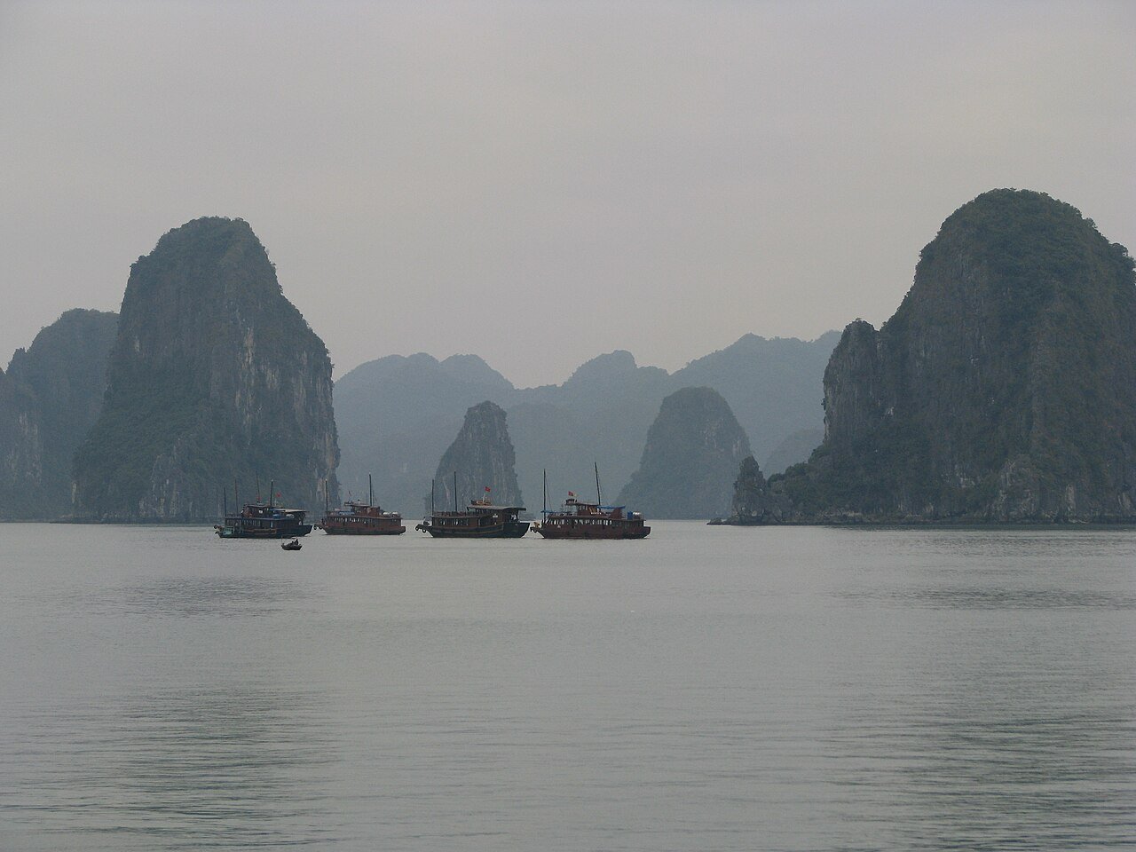 Wooden junk boats among the misty limestone karsts of Ha Long Bay